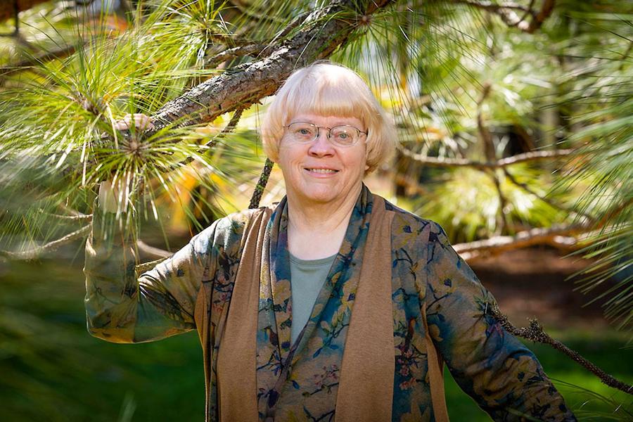 Dr. Carol Miller stands with a longleaf pine last summer at Lovett Pinetum in Strafford, Missouri. During her 40 years of teaching, Miller has taken a special interest in environmental law. (Photo by Kevin White / Missouri State University)